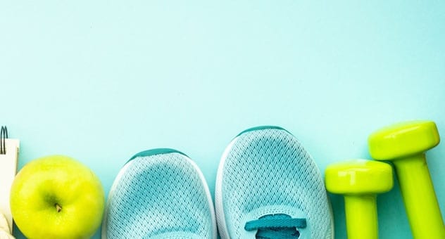 apple, running shoes, hand weights arranged in a line