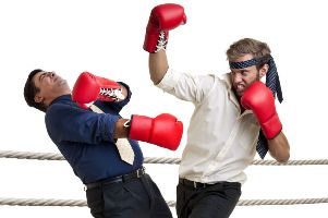 Two men in office attire fight with boxing gloves