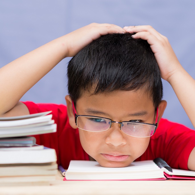 Unhappy schoolboy reading difficult homework