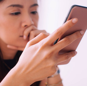 Young woman with worried expression looks at phone