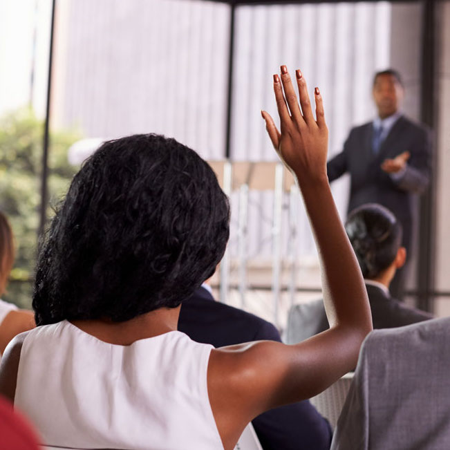 Woman raises hand to ask a question during a presentation