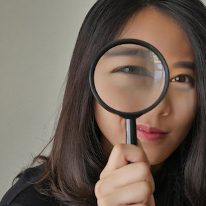 Woman holds magnifying glass to her eye