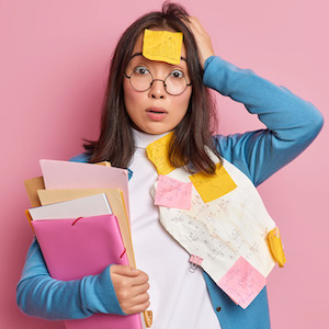 Woman covered in Post-Its is holding documents and looking confused