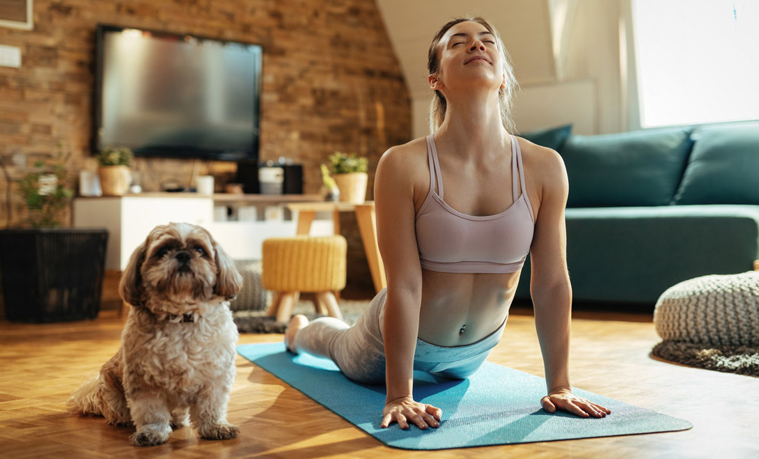 A woman practises yoga with her dog