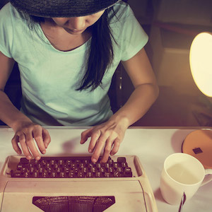 Young female journalist types on typewriter