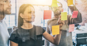 A man and a woman planning something with sticky notes in different colours.
