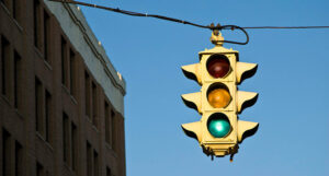 A traffic light hanging against a blue sky. The light is green.