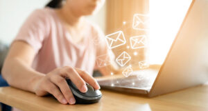 A woman working on her computer. Envelope icons overlay the photo, showing she's working on emails.