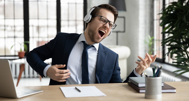 A man playing air guitar at his desk.