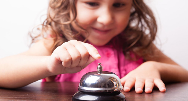 A little girl in a pink t-shirt pushes a bell.