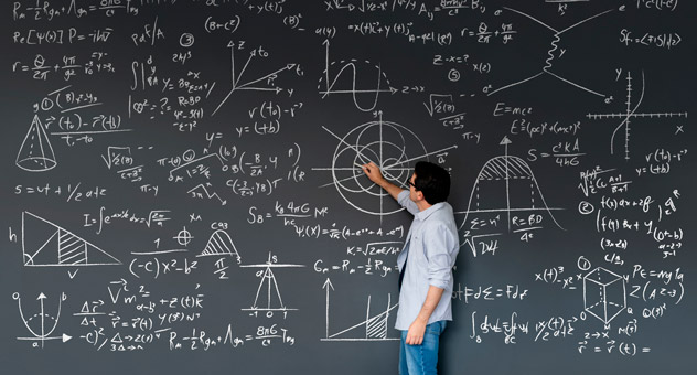 A math teacher writing on a chalkboard full of equations.