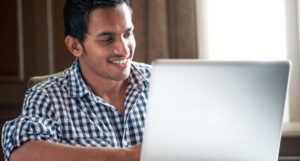 A man at his laptop, smiling.