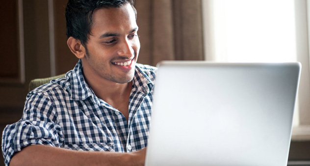 A man at his laptop, smiling.
