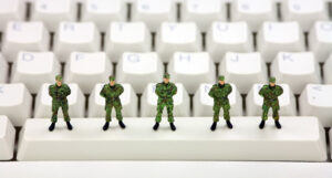 Five toy soldiers on the space bar of a computer keyboard.