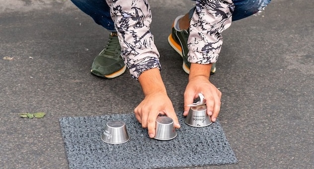 Street magician performs the ball and cup trick