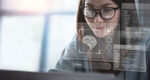 Person with long, dark hair and glasses smiles softly at laptop screen, with reflection of ai tool prompt window over their face