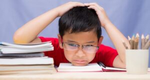 Unhappy schoolboy reading difficult homework